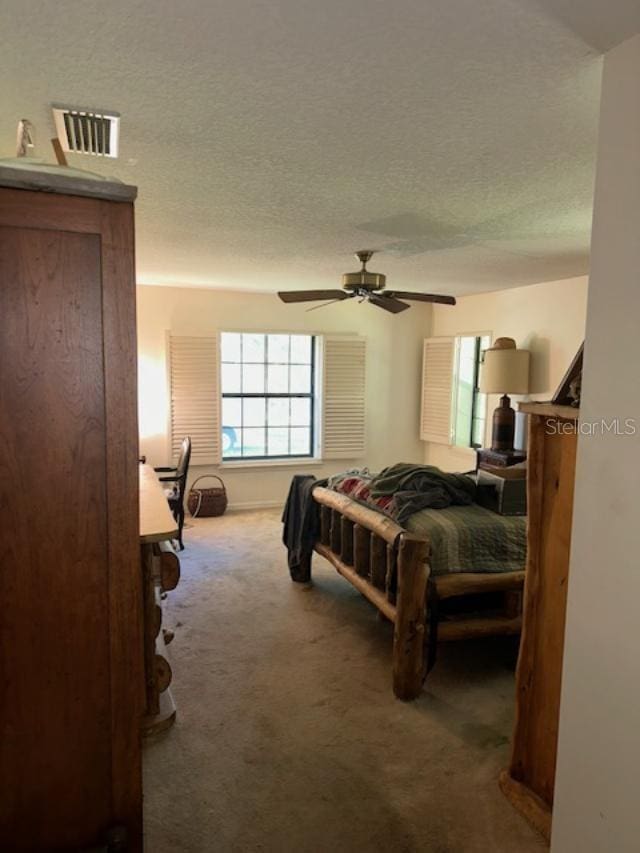 bedroom with ceiling fan, carpet, and a textured ceiling