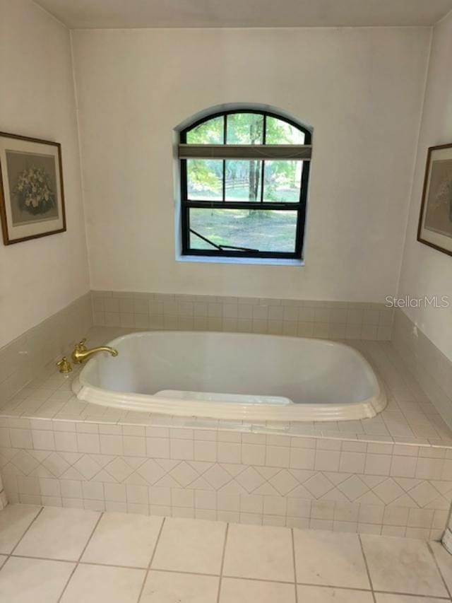 bathroom with tiled bath and tile patterned flooring