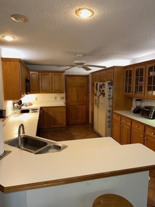 kitchen with a textured ceiling, white fridge, kitchen peninsula, and sink