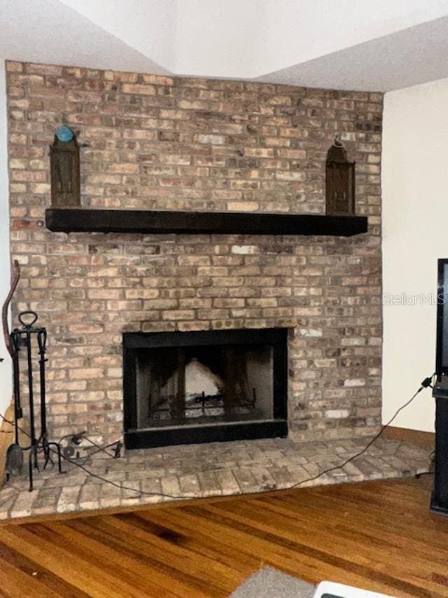 room details featuring wood-type flooring and a brick fireplace