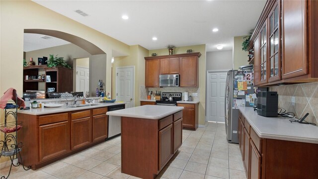 kitchen with stainless steel appliances, backsplash, a center island, and sink