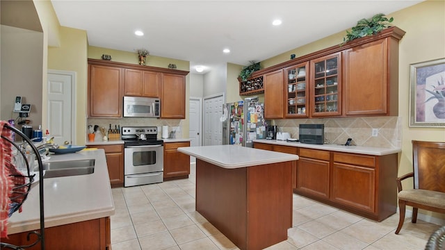 kitchen with decorative backsplash, stainless steel appliances, a center island, and light tile patterned floors