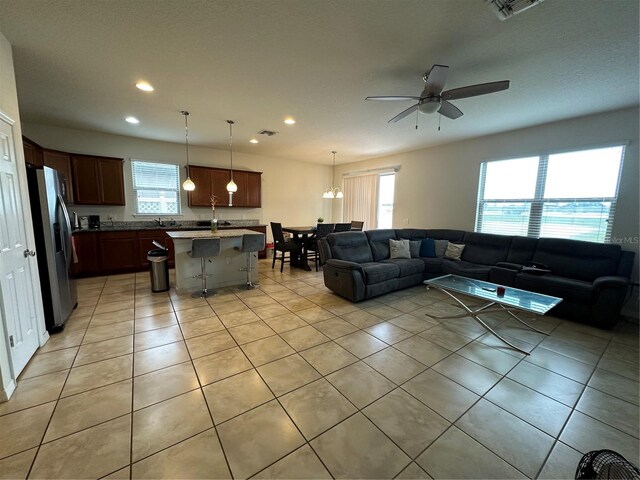 living room with sink, light tile patterned floors, and ceiling fan with notable chandelier