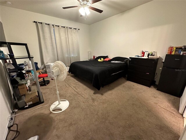 bedroom with carpet, ceiling fan, and black fridge