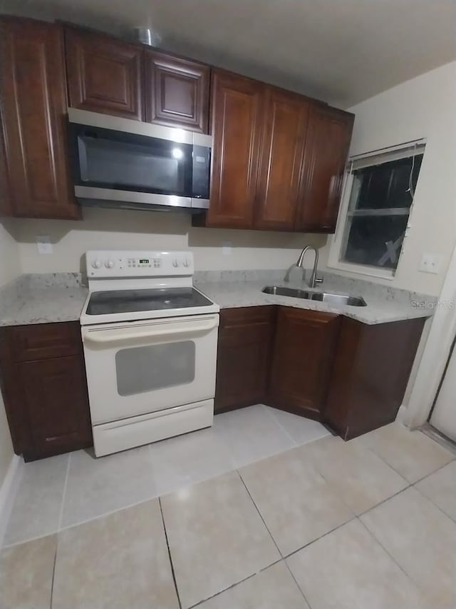 kitchen featuring light tile patterned flooring, dark brown cabinets, white electric stove, and sink