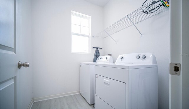 clothes washing area with independent washer and dryer and light hardwood / wood-style flooring