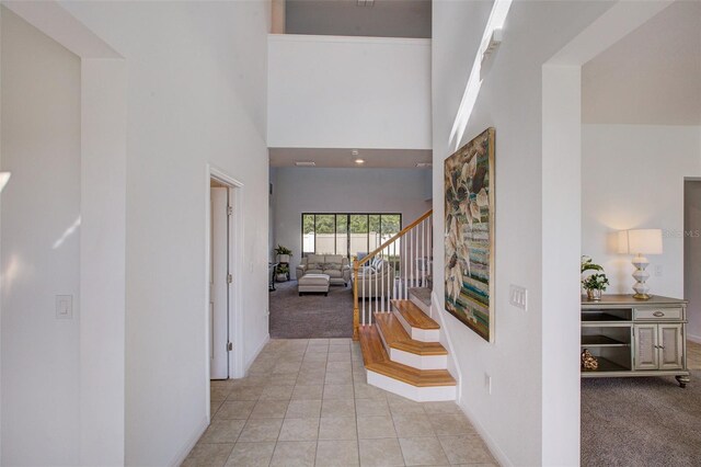 corridor with a high ceiling and light colored carpet