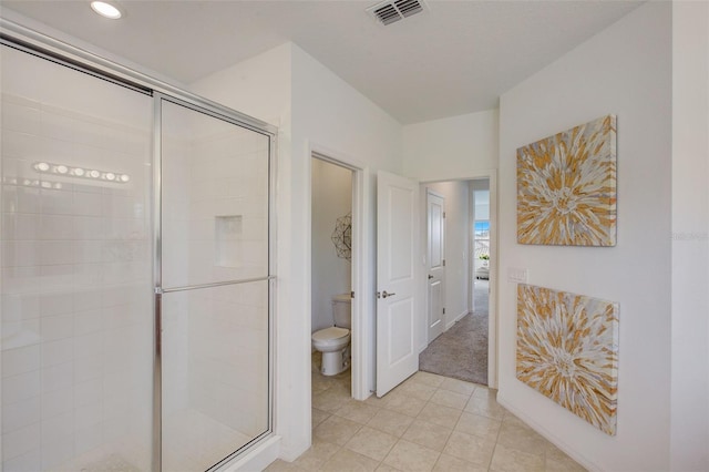 bathroom with a shower with shower door, toilet, and tile patterned floors