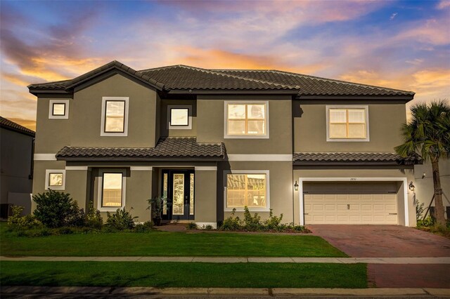 mediterranean / spanish-style home featuring a garage and a yard