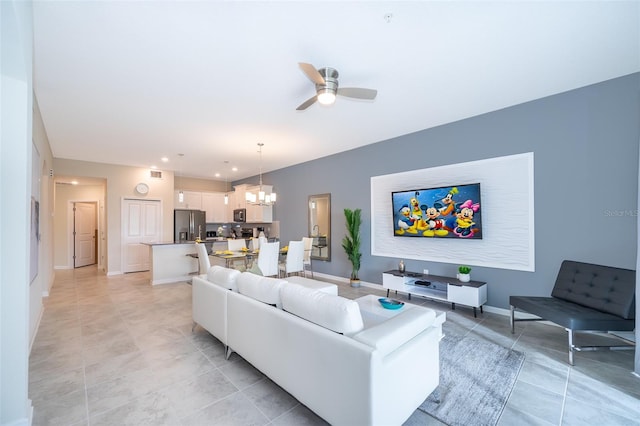 living room featuring light tile patterned flooring and ceiling fan with notable chandelier