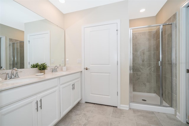 bathroom with a shower with shower door, tile patterned floors, and double sink vanity