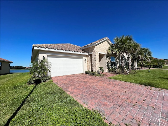 mediterranean / spanish-style house with a front yard, a garage, and a water view