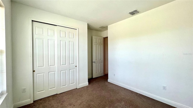 unfurnished bedroom with a closet and dark colored carpet