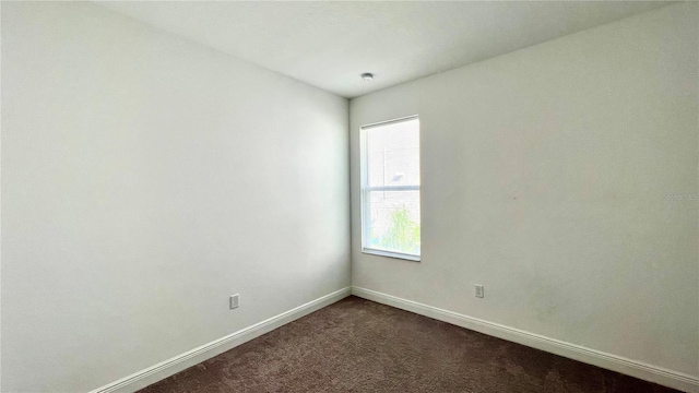 unfurnished room featuring dark carpet