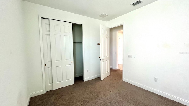 unfurnished bedroom featuring dark carpet and a closet