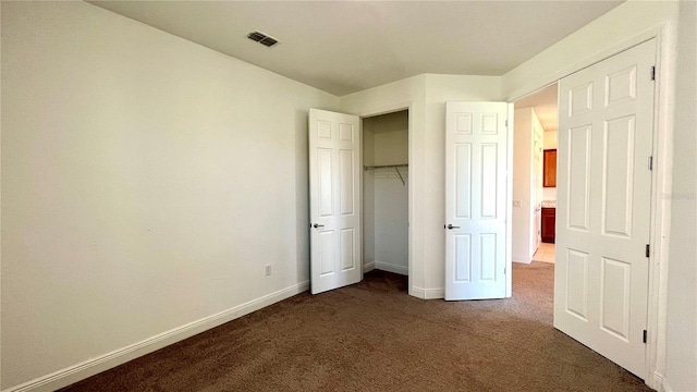 unfurnished bedroom featuring dark carpet and a closet