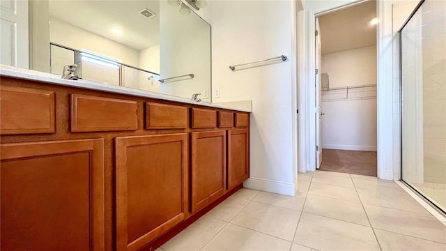 bathroom with an enclosed shower, vanity, and tile patterned flooring