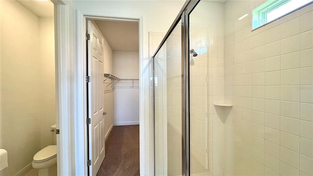 bathroom featuring a shower with shower door and toilet