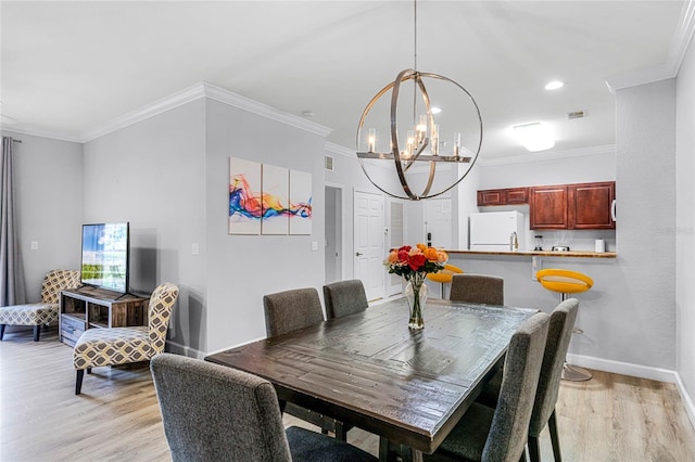 dining space with a notable chandelier, crown molding, and light hardwood / wood-style flooring