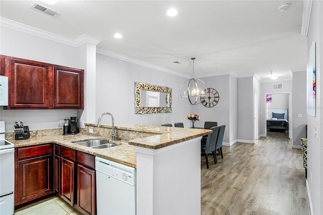 kitchen featuring sink, a notable chandelier, kitchen peninsula, light hardwood / wood-style floors, and white appliances