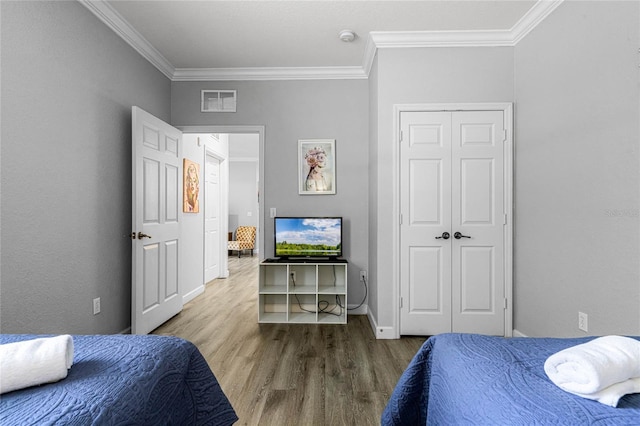 bedroom featuring a closet, wood-type flooring, and ornamental molding