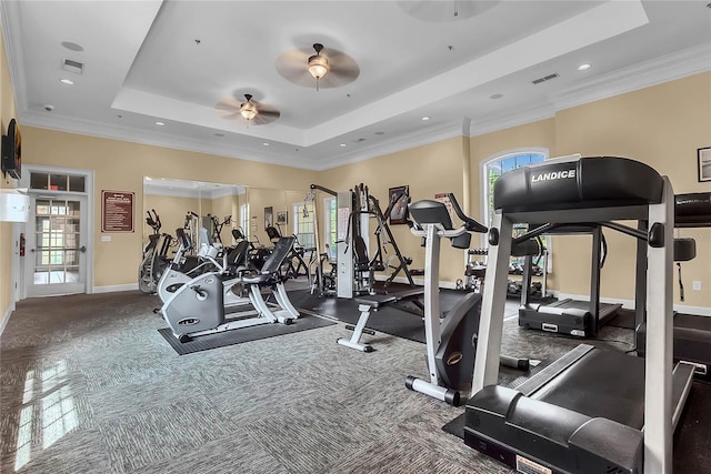 workout area featuring a raised ceiling, ceiling fan, and crown molding