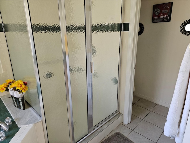 bathroom with a shower with door and tile patterned flooring