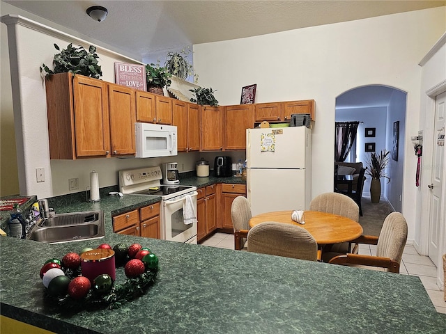 kitchen featuring a textured ceiling, light tile patterned floors, sink, and white appliances