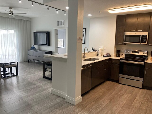 kitchen featuring dark brown cabinetry, appliances with stainless steel finishes, sink, and light wood-type flooring