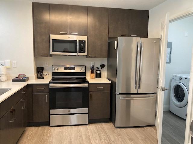 kitchen featuring light wood-type flooring, washer / clothes dryer, dark brown cabinets, and appliances with stainless steel finishes