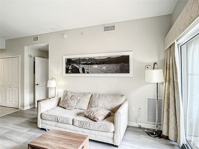 living room with wood finished floors, visible vents, and baseboards