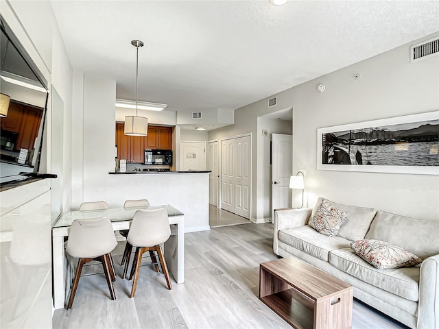 living room featuring light wood-style flooring, visible vents, and baseboards