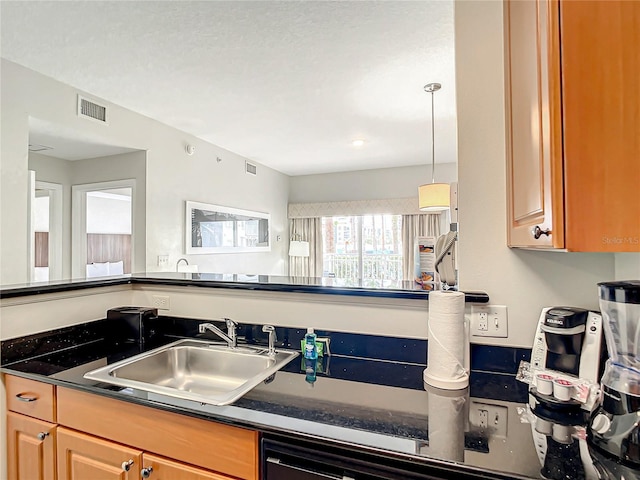 kitchen featuring dark countertops, visible vents, and a sink