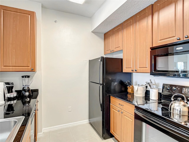 kitchen with black appliances, light tile patterned floors, baseboards, and a sink