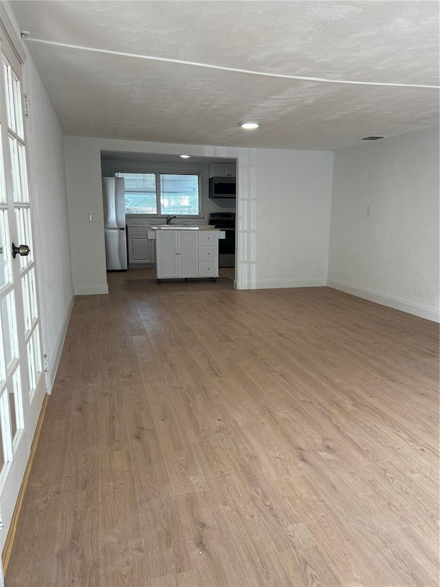 unfurnished living room featuring sink and light wood-type flooring