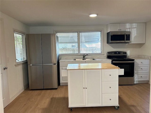 kitchen with white cabinets, light hardwood / wood-style floors, sink, and appliances with stainless steel finishes