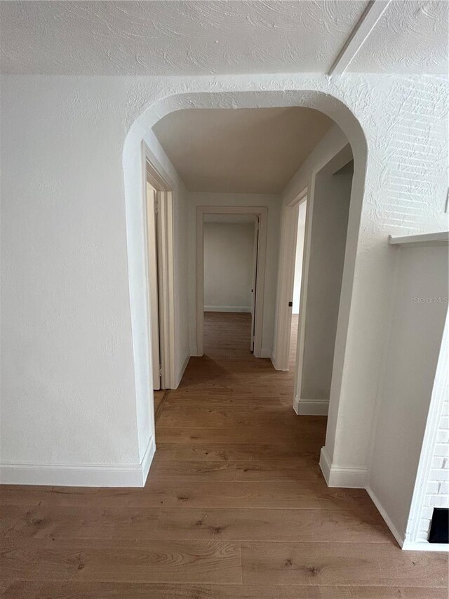 hall with wood-type flooring and a textured ceiling