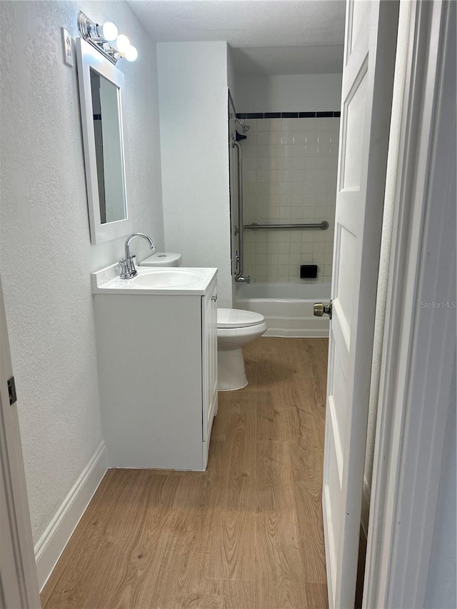 full bathroom with tiled shower / bath, toilet, vanity, and hardwood / wood-style flooring