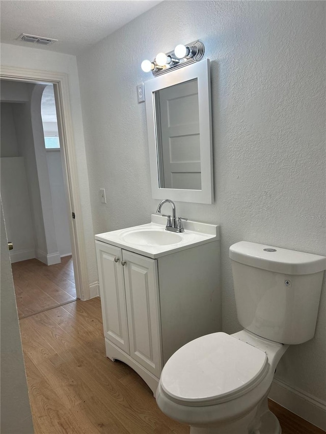 bathroom with hardwood / wood-style floors, vanity, a textured ceiling, and toilet