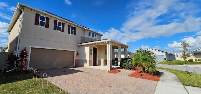 view of front facade with decorative driveway, a garage, and stucco siding