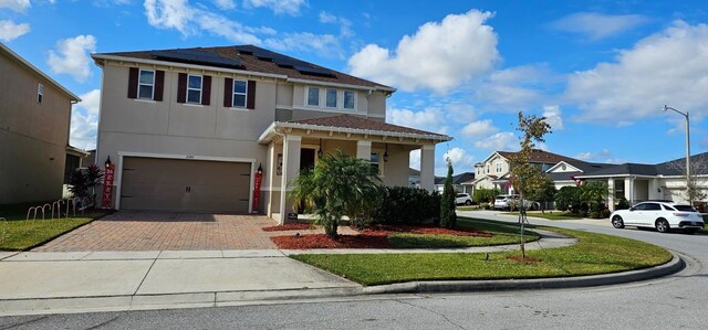 view of front of property featuring stucco siding, decorative driveway, roof mounted solar panels, a residential view, and a garage