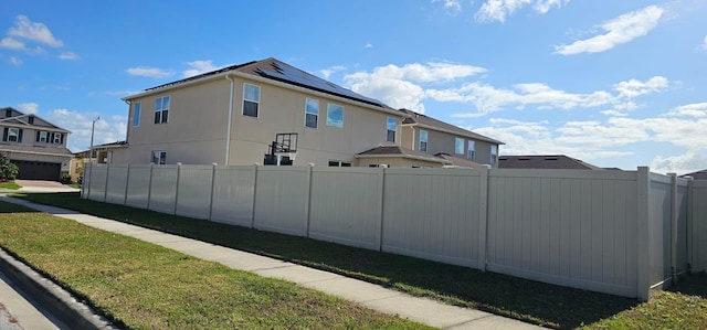 exterior space with fence, solar panels, a yard, stucco siding, and a residential view