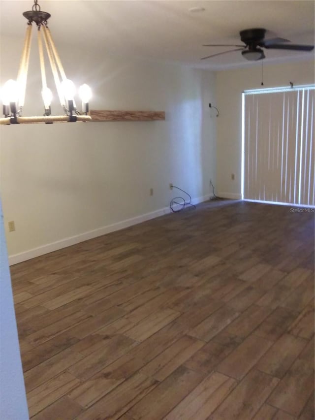 spare room featuring dark hardwood / wood-style flooring and ceiling fan with notable chandelier