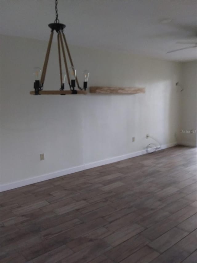 unfurnished room with an inviting chandelier and dark hardwood / wood-style flooring