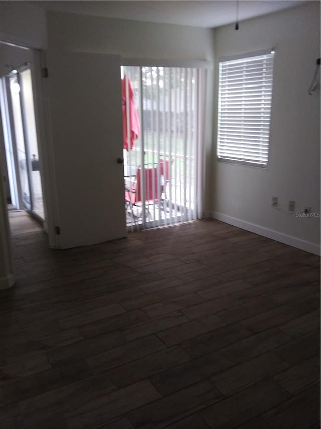 spare room featuring a healthy amount of sunlight and dark wood-type flooring