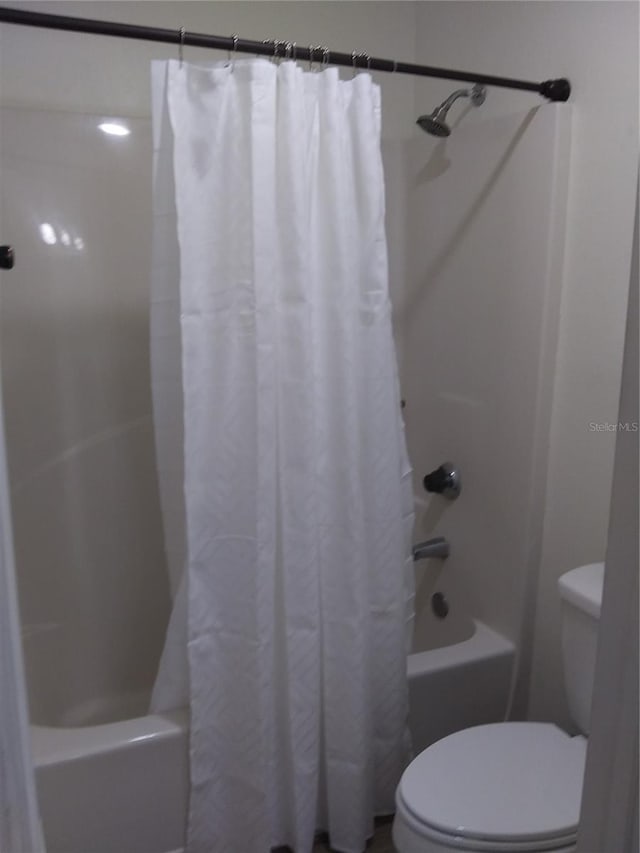 bathroom featuring toilet and shower / bath combo with shower curtain