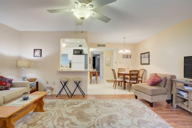 living room featuring light hardwood / wood-style flooring and ceiling fan with notable chandelier