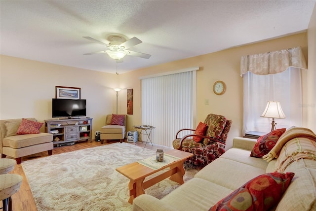 living room with hardwood / wood-style floors, ceiling fan, and a textured ceiling