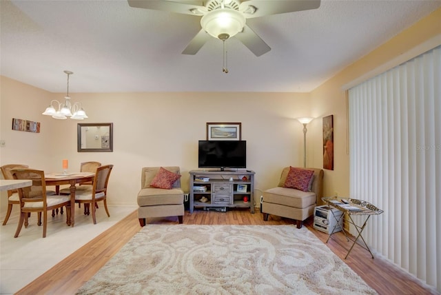 living room with hardwood / wood-style floors and ceiling fan with notable chandelier