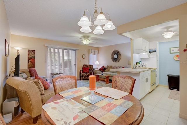 tiled dining area with ceiling fan with notable chandelier